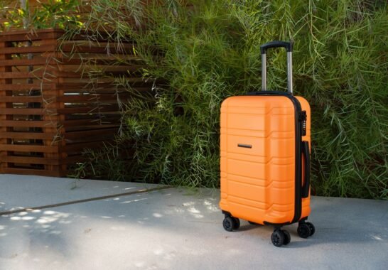 an orange piece of luggage sitting on top of a sidewalk