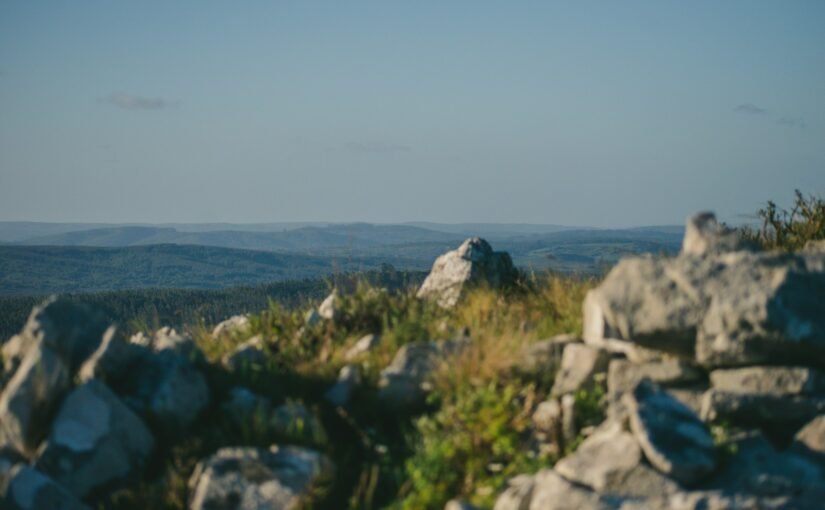 a rocky outcropping with a view of mountains in the distance